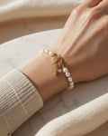 Close-up of a person wearing a pearl bracelet on a light background