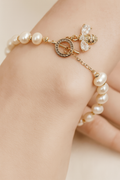 Pearl bracelet with gold accents on a hand against a neutral background