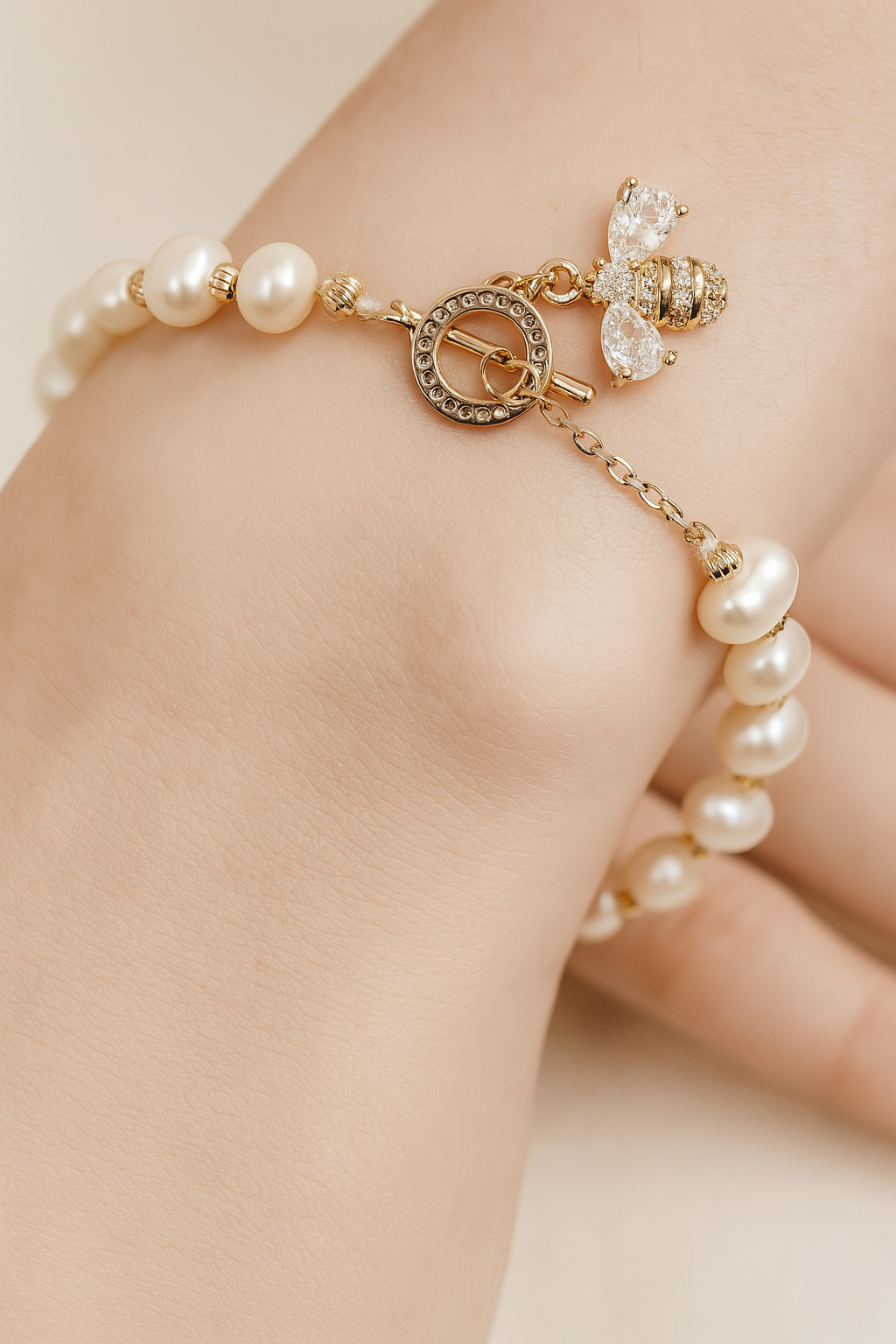 Pearl bracelet with gold accents on a hand against a neutral background