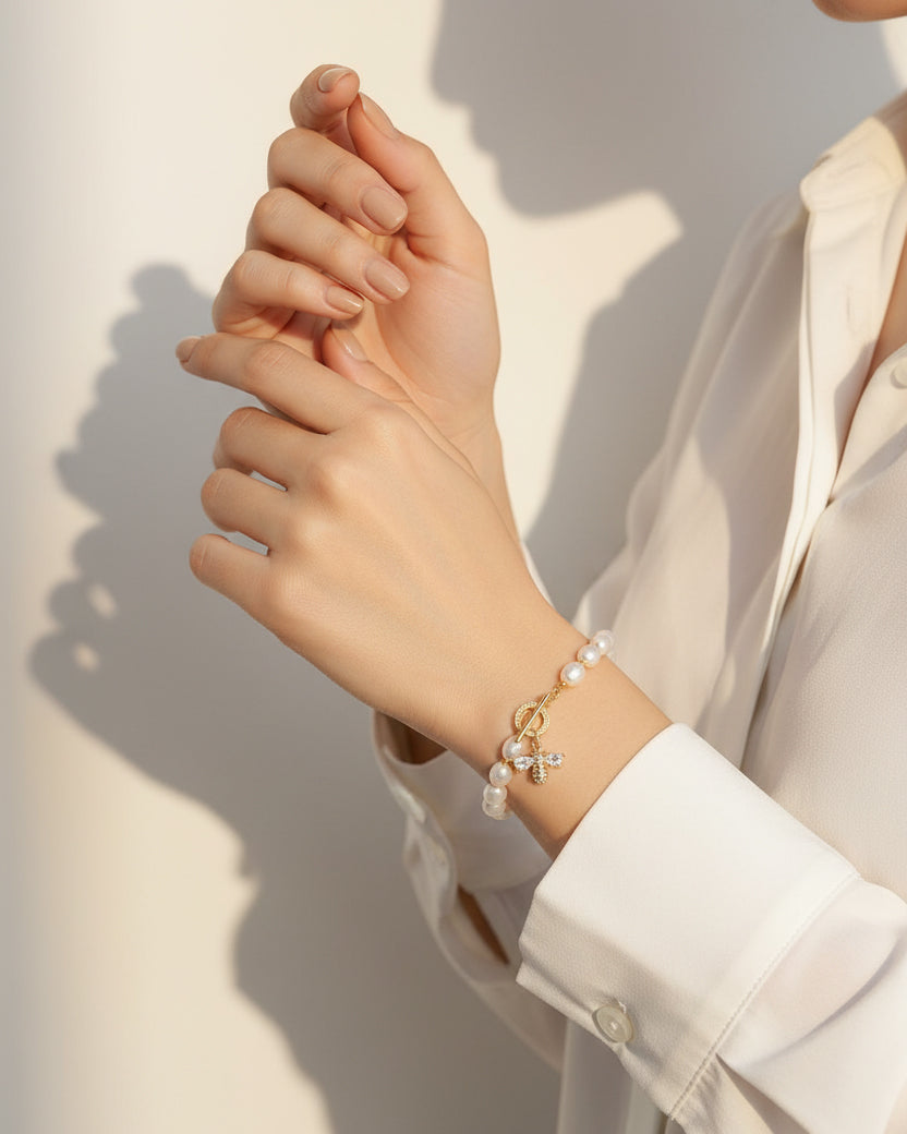 Close-up of a person wearing a pearl bracelet on a light background