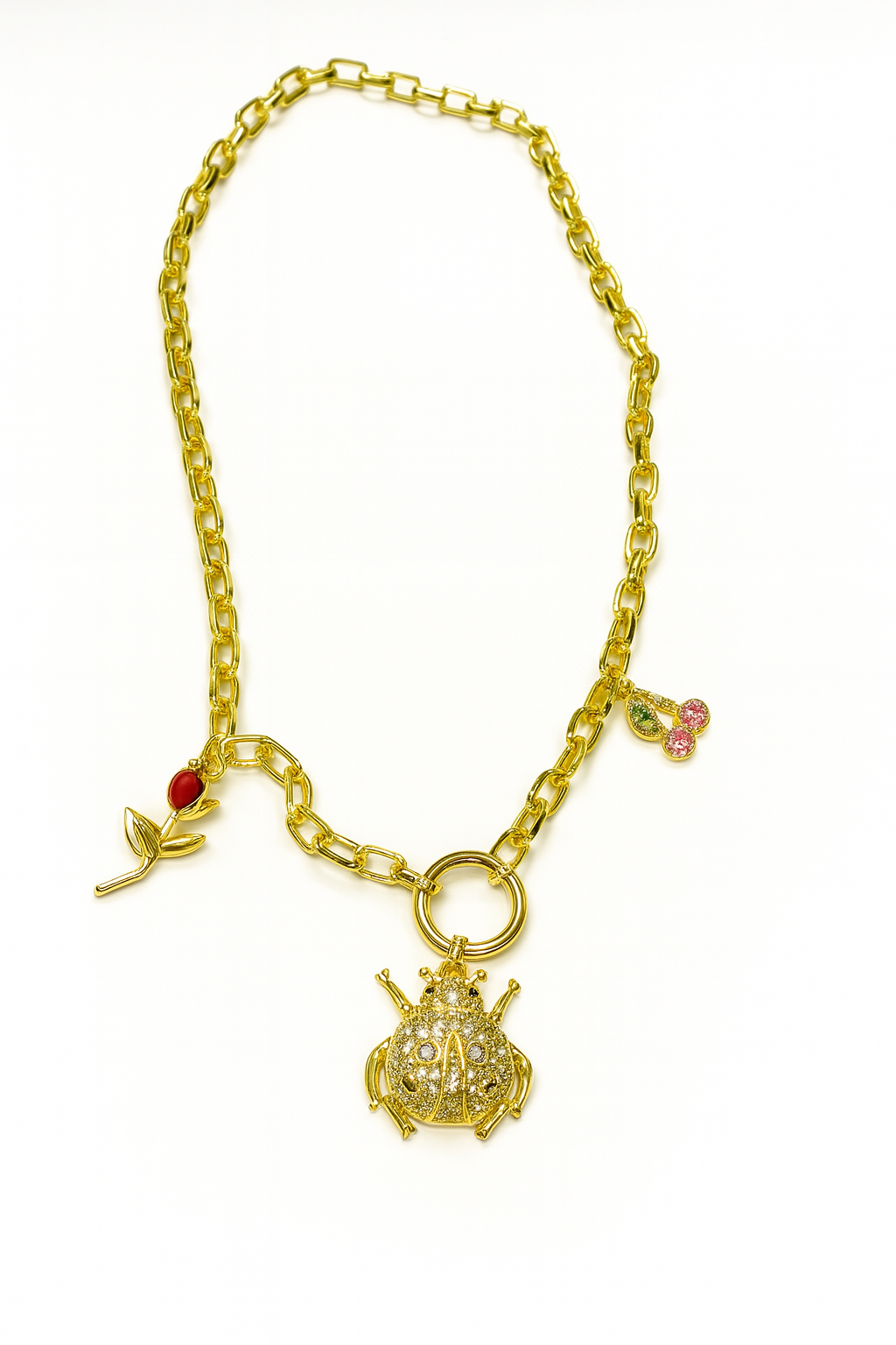 Beetle Jardin gold necklace with beetle, cherry, and rose pendants on rectangular chain.