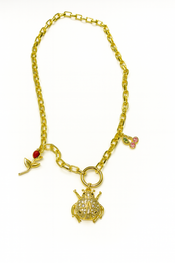 Beetle Jardin gold necklace with beetle, cherry, and rose pendants on rectangular chain.
