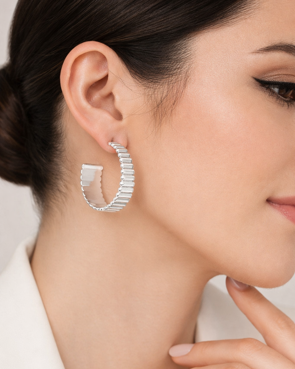 Model wearing silver ribbed hoop earrings with bold textured design