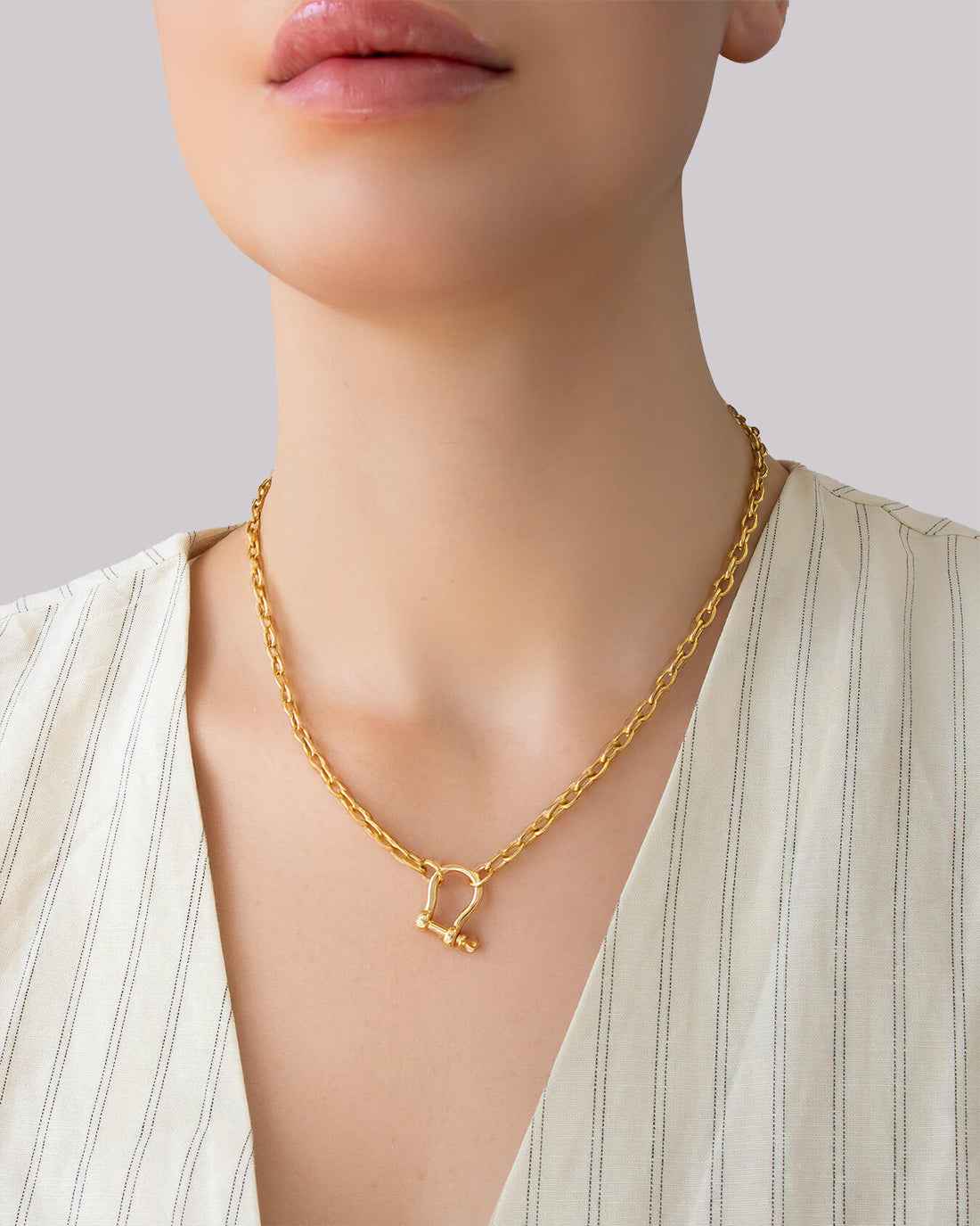 Gold shackle pendant chain necklace on model, featuring a chunky gold chain and minimalist shackle clasp by Jadejuri