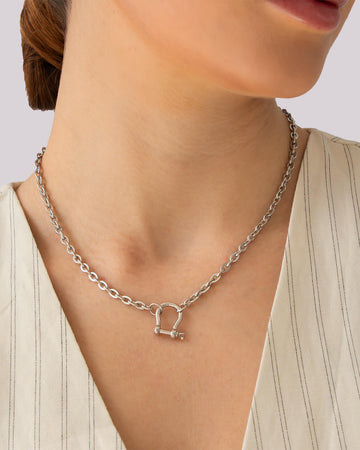 Model wearing silver chain necklace with bold shackle pendant and polished silver-plated finish