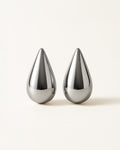 A pair of silver bold teardrop stud earrings with smooth sculptural surface, displayed against a soft neutral background.