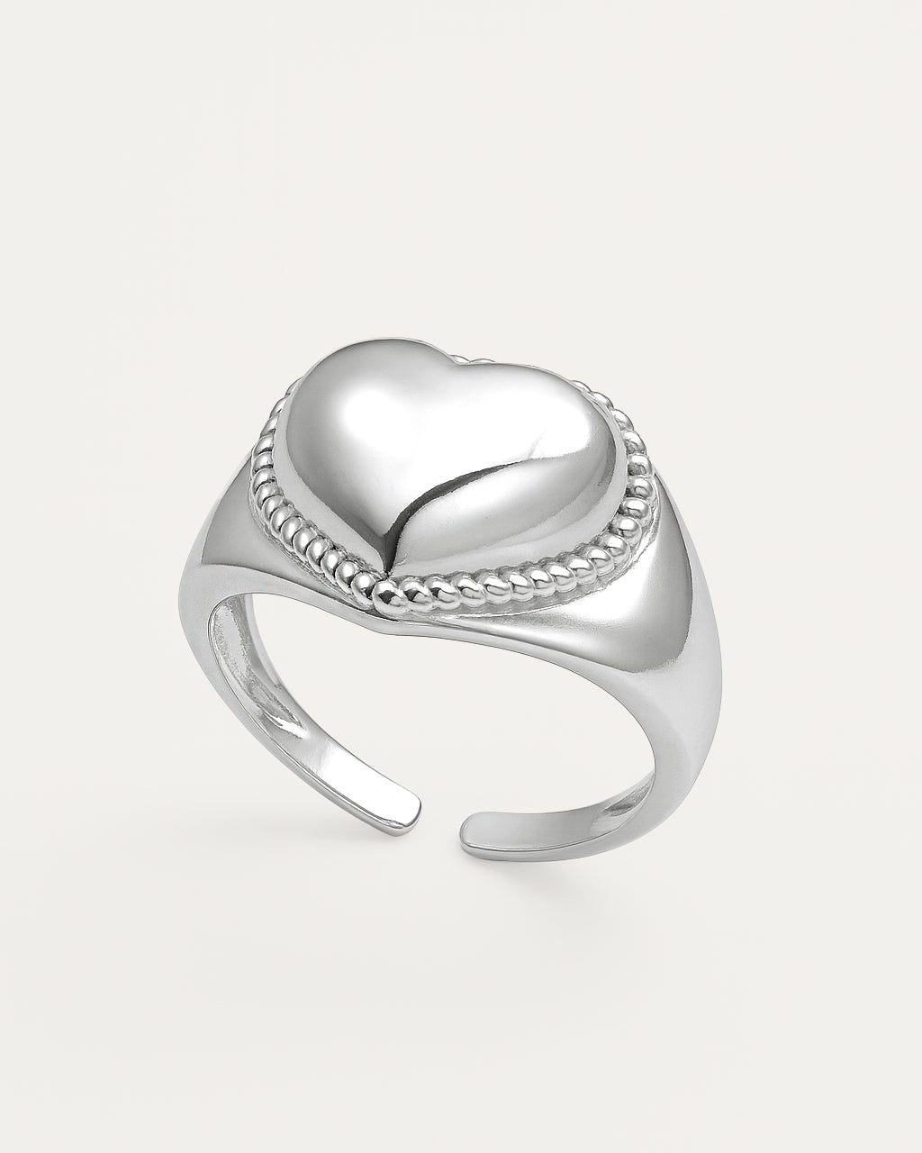 Silver heart-shaped ring on a light gray background