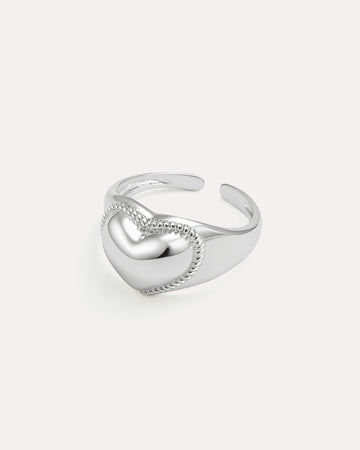 Silver heart-shaped ring on a light gray background