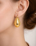 Gold teardrop earrings with beaded detail worn on ear minimalist jewelry