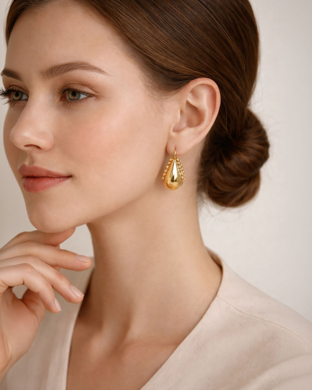 Gold teardrop earrings with beaded detail worn on ear minimalist style