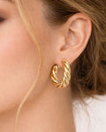 Gold rope hoop earrings with twisted design worn on ear minimalist style