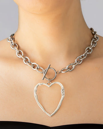 Model wearing silver chunky choker with oversized sculptural heart pendant – organic and bold statement necklace.