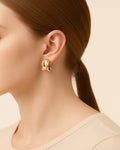 Gold hoop earring worn by a person with a neutral background