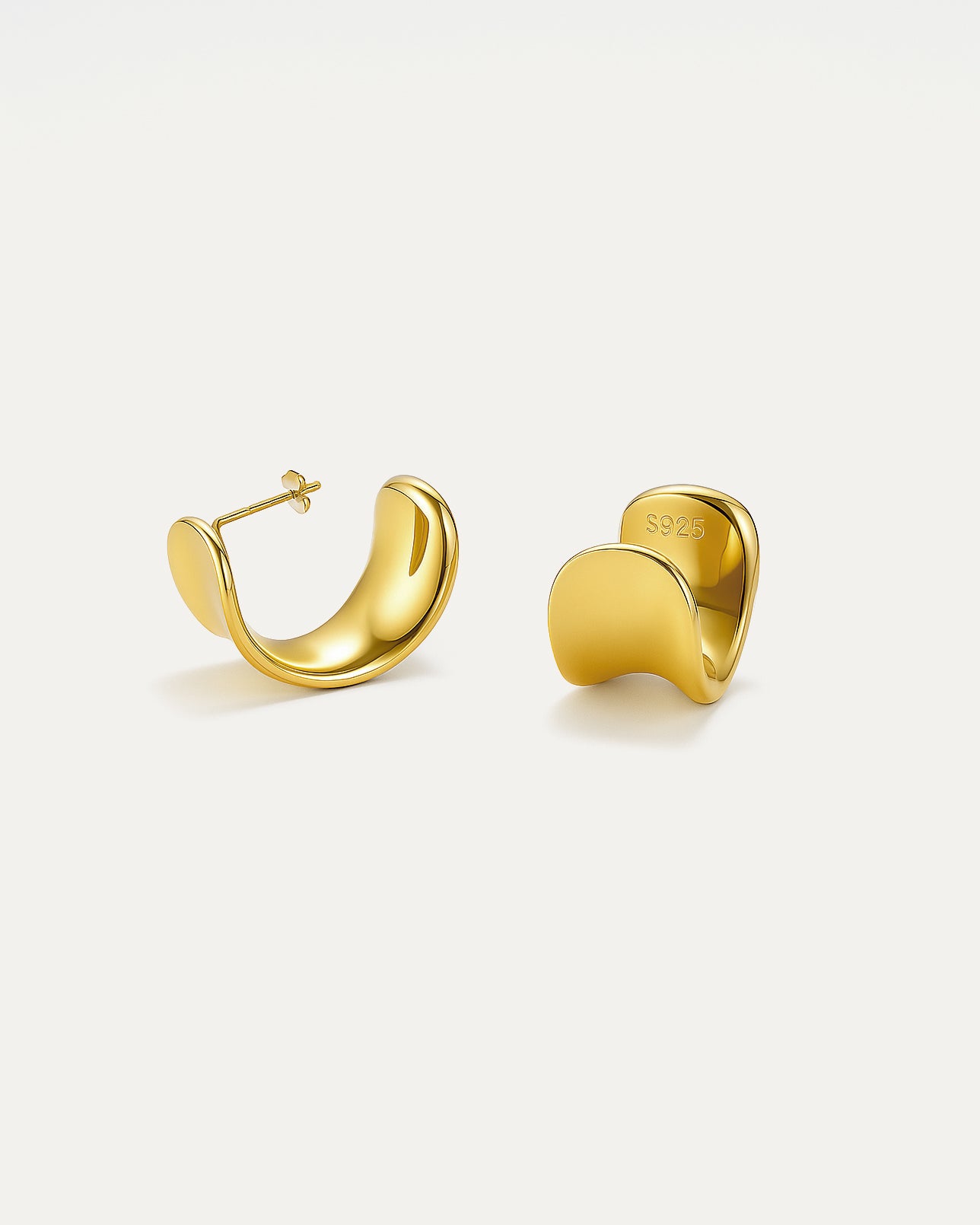 Gold hoop earrings on a light beige background