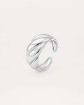 A close-up studio shot of a chunky, adjustable silver-tone cuff ring on a plain white or light beige background. The band fea