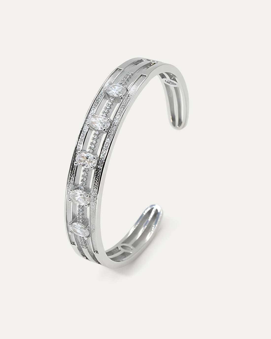 A silver-plated cuff bracelet with a modern, open design. It features a central pave-set micro-crystal band with five spaced 