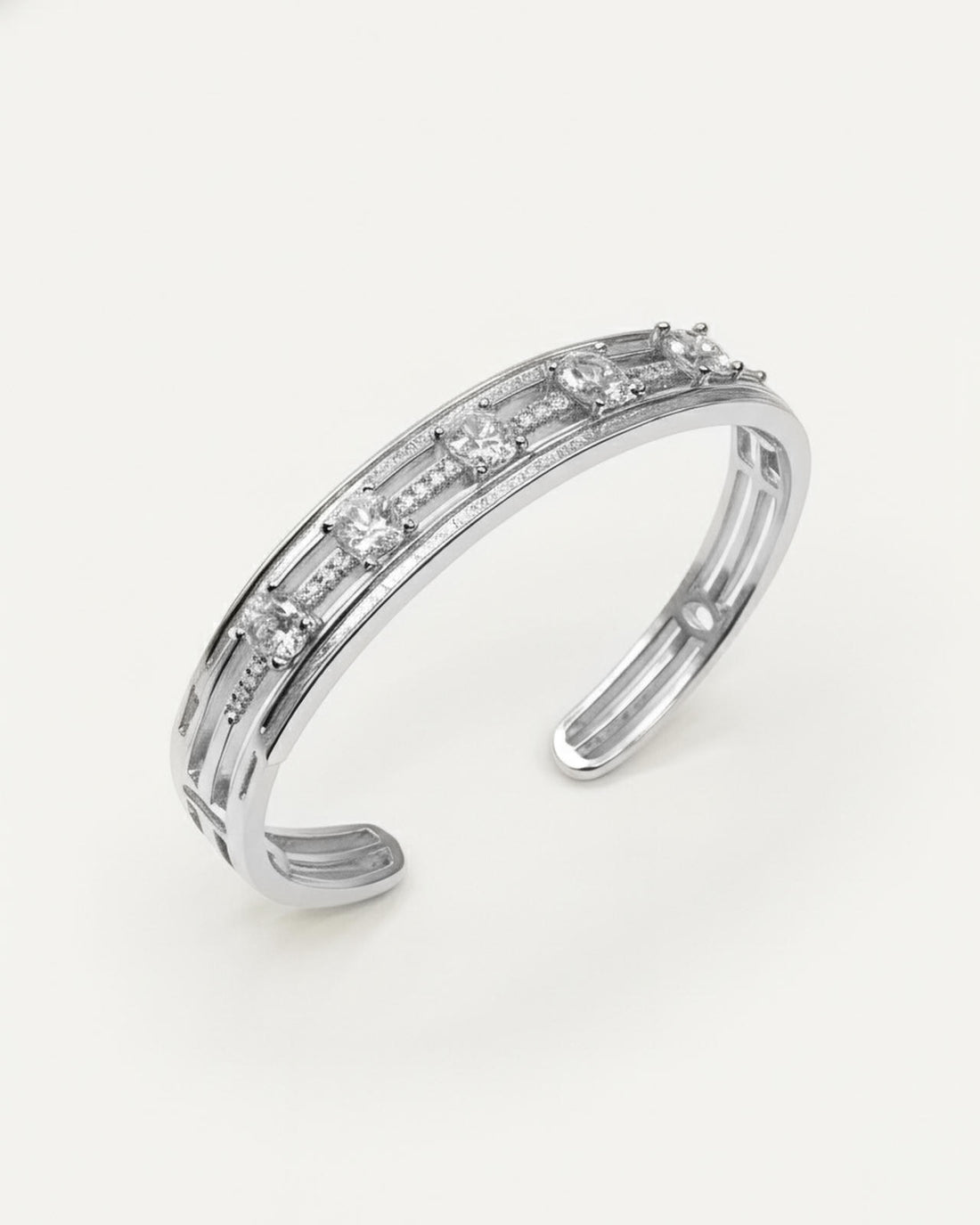 A silver-plated cuff bracelet with a modern, open design. It features a central pave-set micro-crystal band with five spaced 