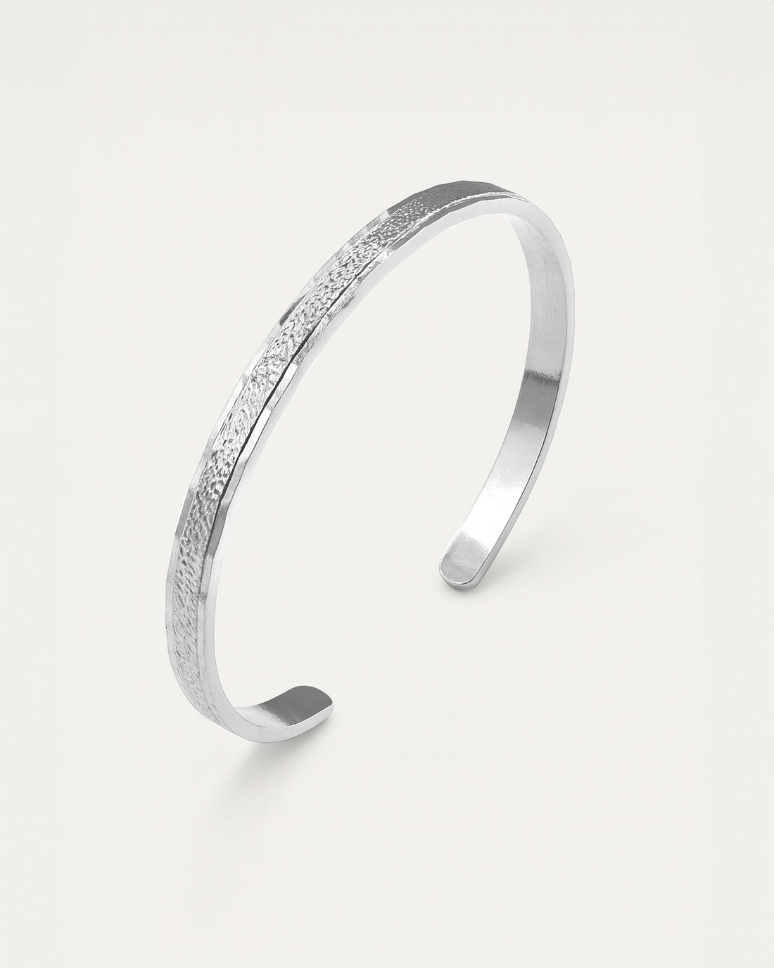 Silver bracelet with textured surface on a light gray background