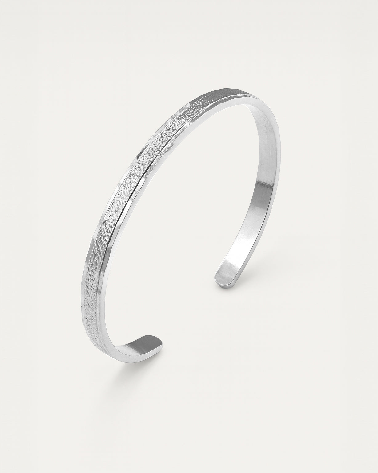 Silver bracelet with textured surface on a light gray background