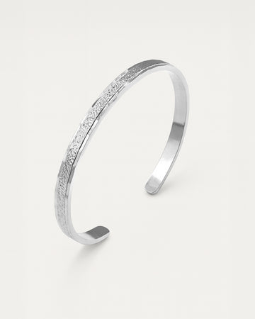 Silver bracelet with textured surface on a light gray background