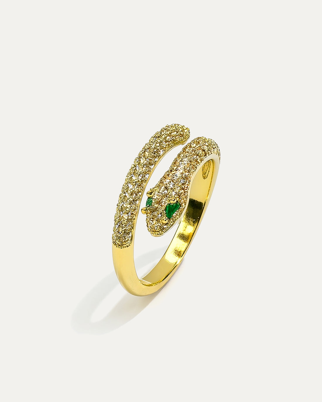 A close-up studio shot of a gold-tone ring shaped like a snake on a plain white background. The ring has a wrap-around design