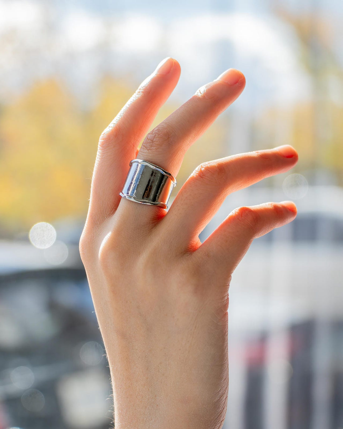 silver-plated wide band statement ring with curved top and open back design on white background