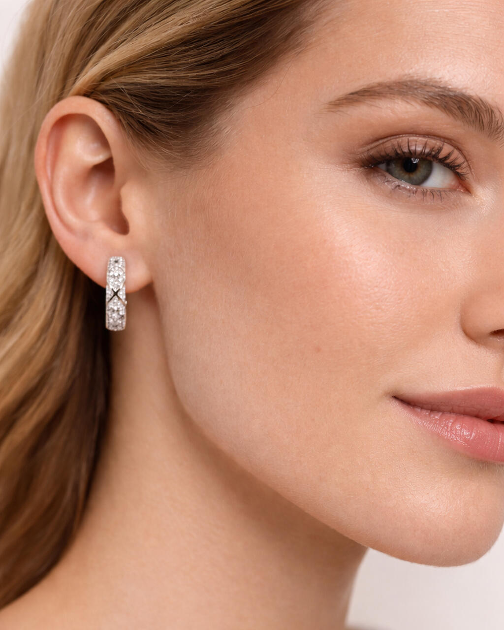 Model wearing silver pavé hoop earrings with diamond-like detailing and polished silver finish