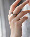 Close-up of a woman's hand wearing a minimalist silver-tone 'Duo Drop' open cuff ring, showcasing the highly polished, organi