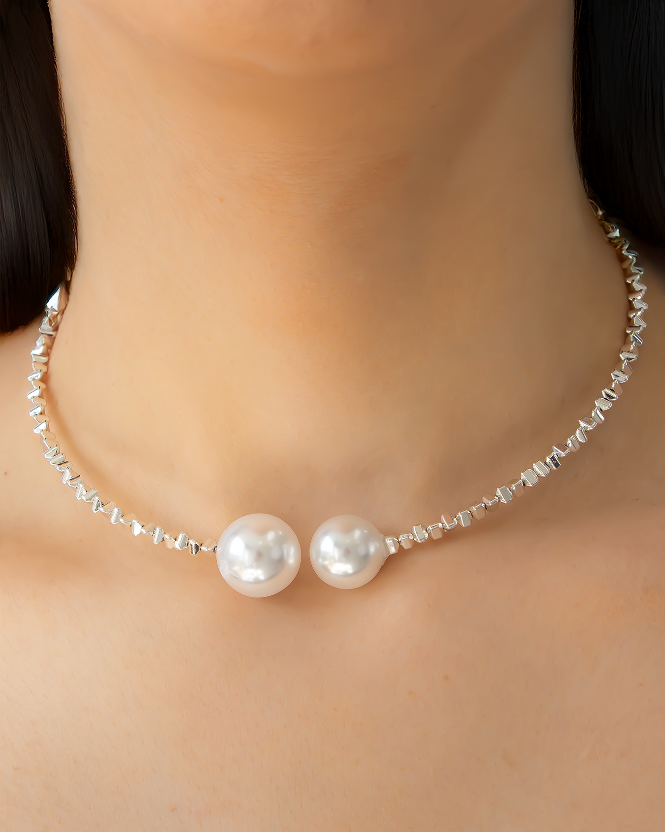 Close-up of a pearl choker necklace featuring two oversized faux pearls and a silver-tone beaded strand, worn on a woman's neck.