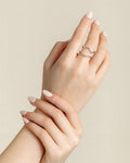 Hand wearing a silver ring on a beige background