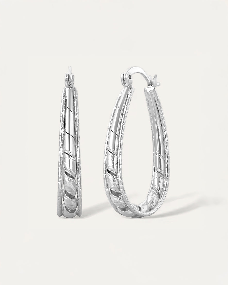 Close-up of silver etched twist oval hoop earrings with carved detailing