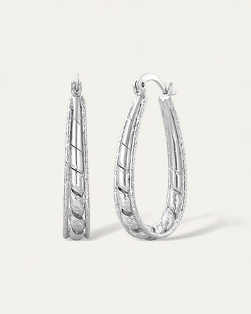 Close-up of silver etched twist oval hoop earrings with carved detailing