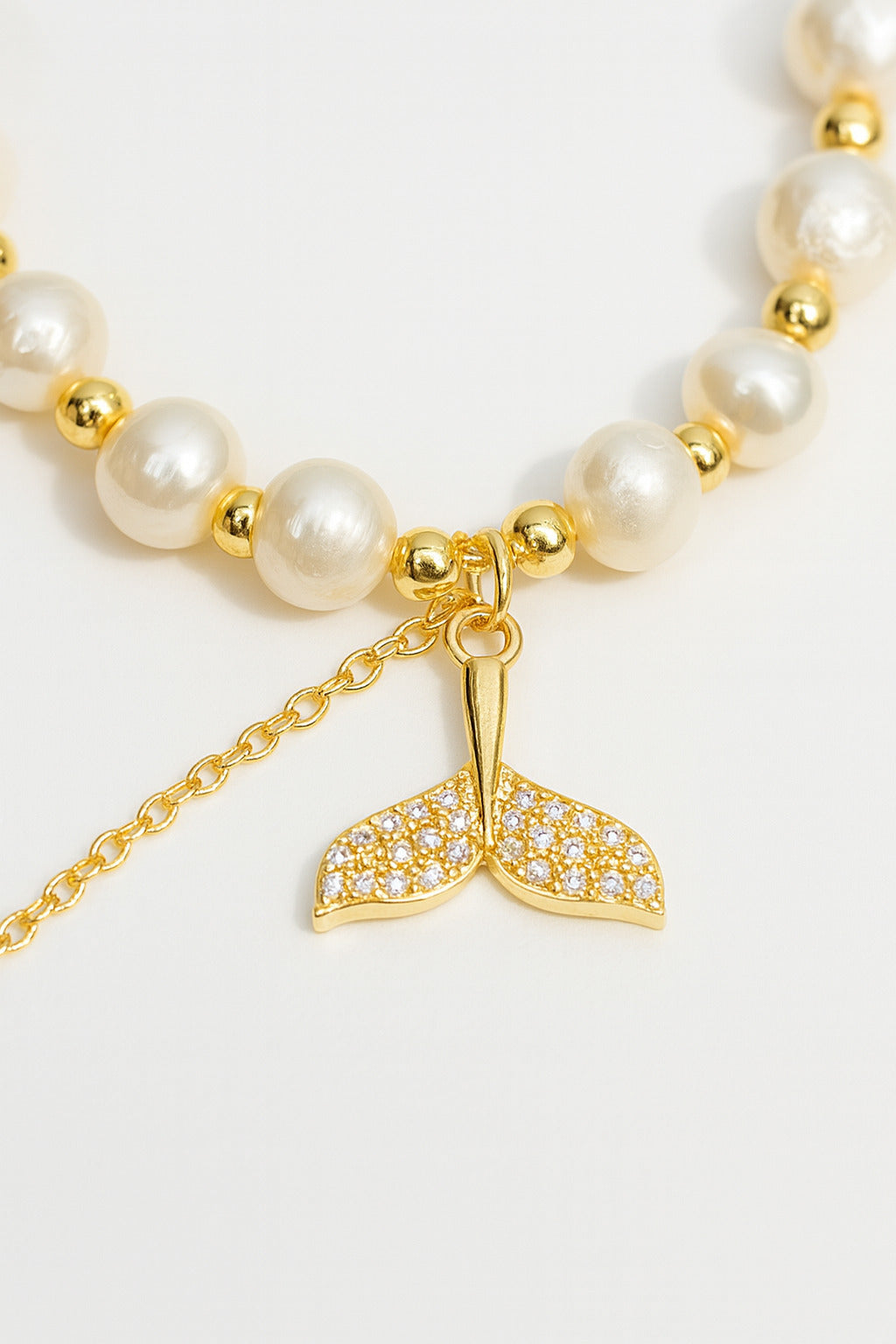 18K gold-plated pearl bracelet featuring a crystal-embellished fish tail charm with adjustable chain detail by Jadejuri