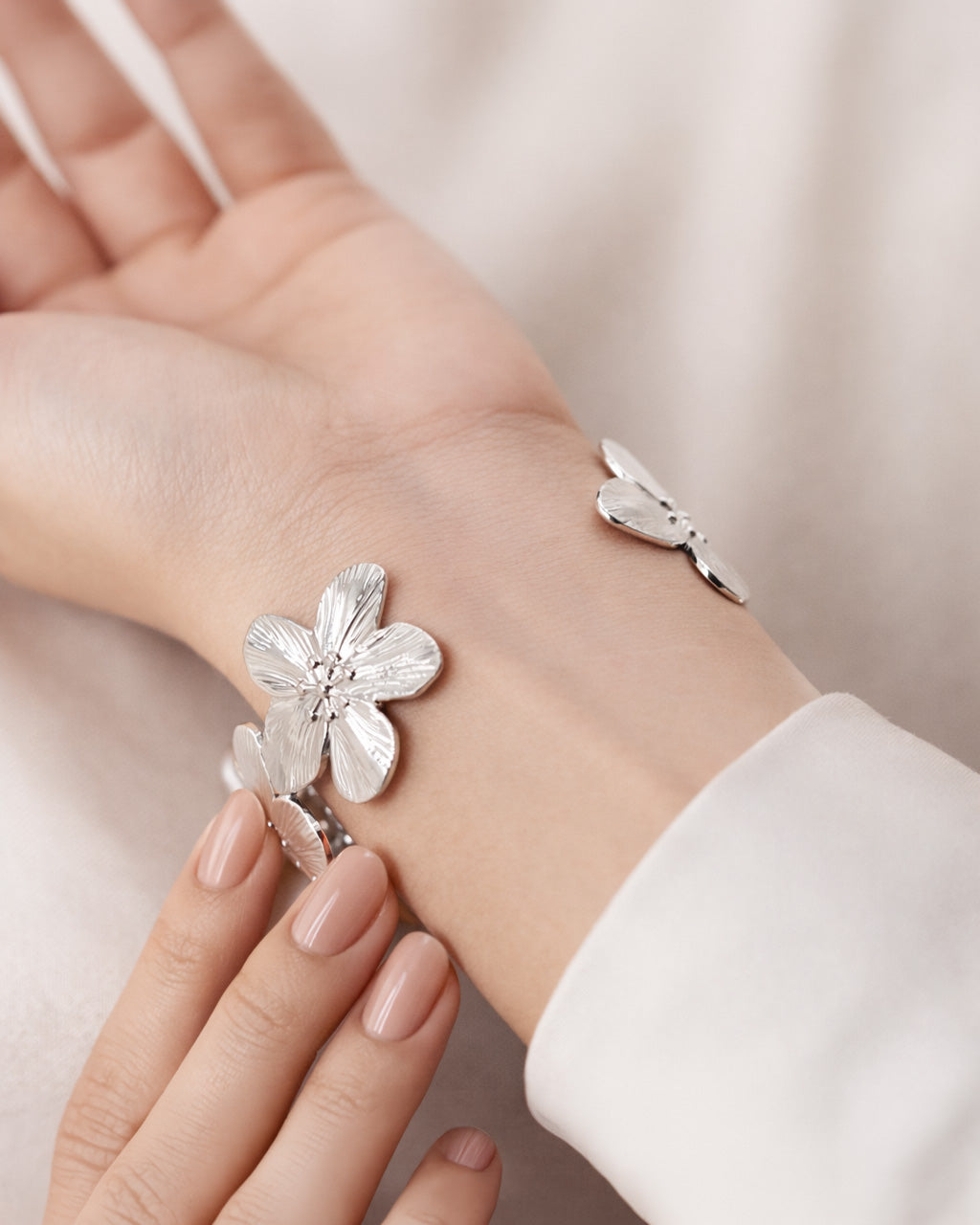 Silver-plated floral cuff bracelet on wrist, flower design statement bangle women