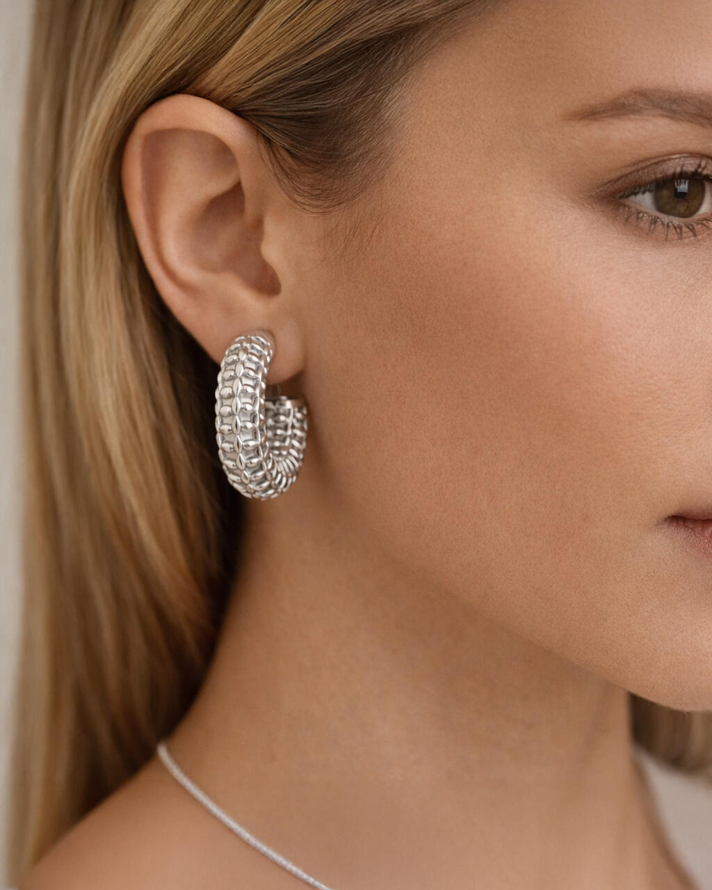 Model wearing silver-plated floral lattice hoop earrings featuring a bold sculpted petal texture and chunky curved hoop desig