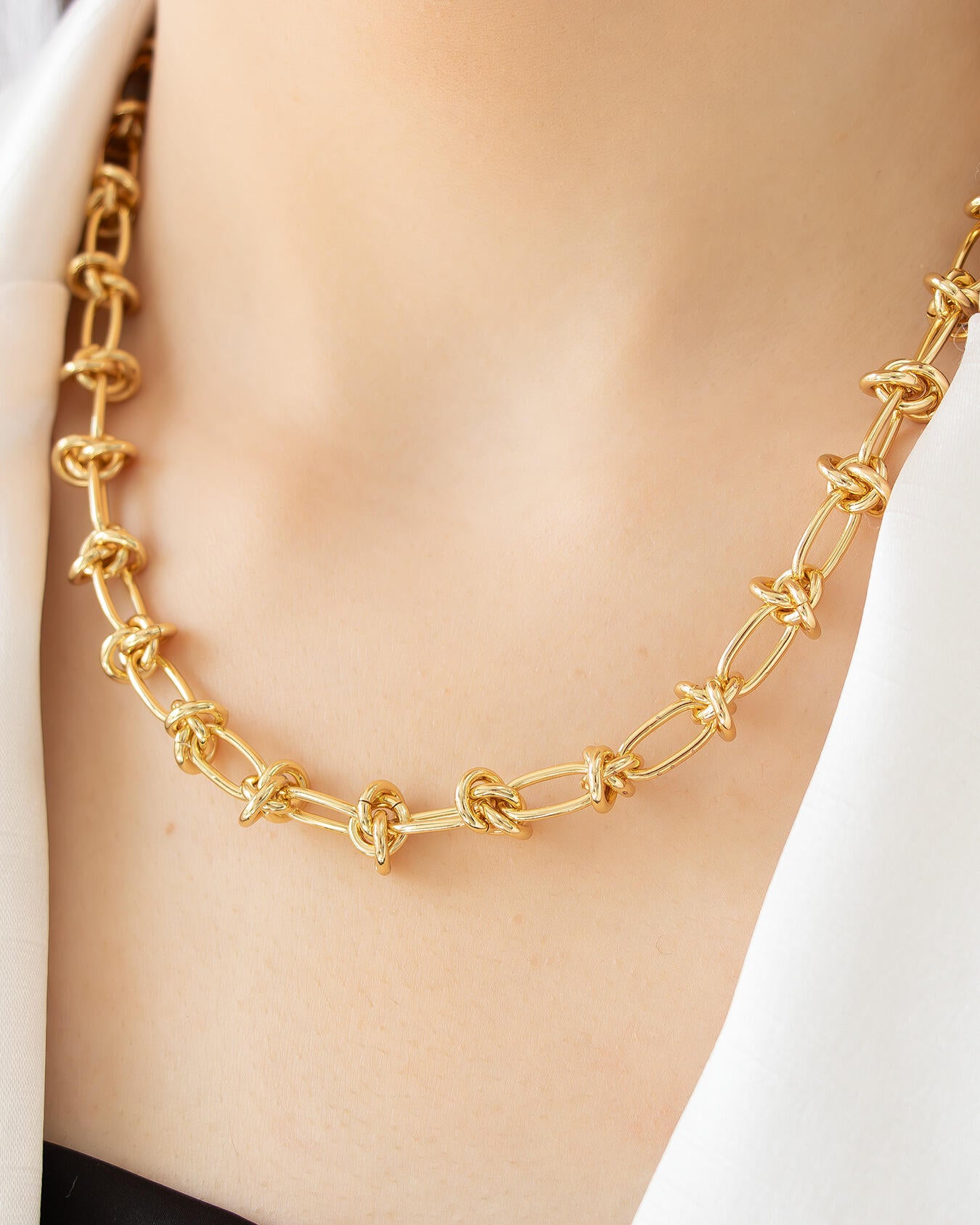 Gold knot link chain necklace close-up on model, featuring polished gold links with knot details by Jadejuri