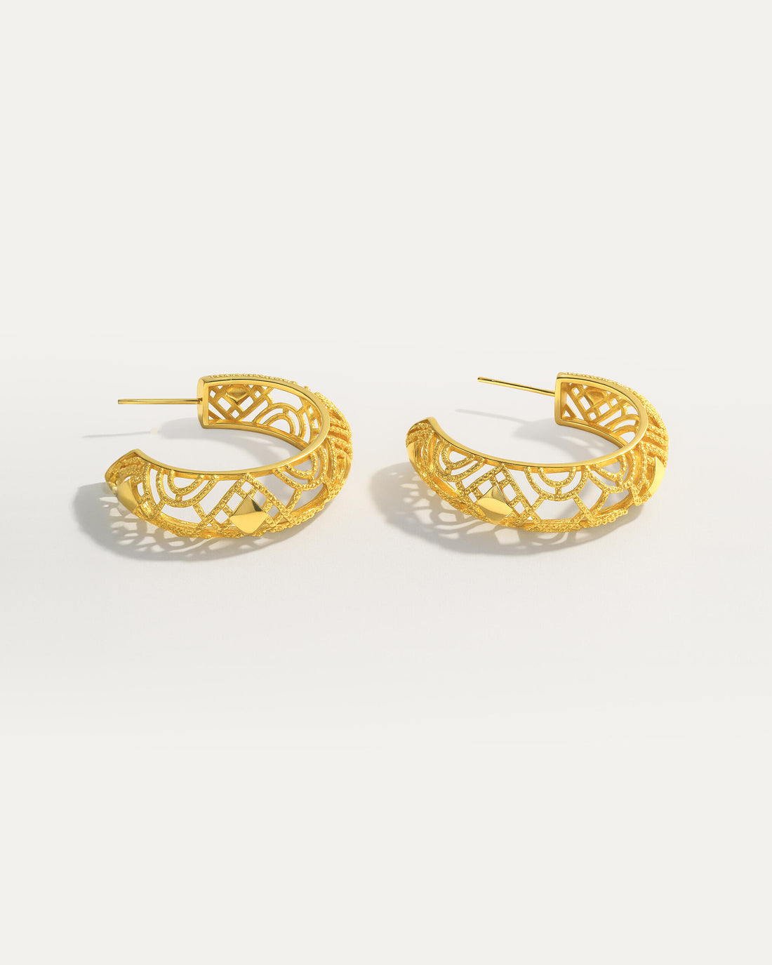 18K gold-plated openwork hoop earrings with geometric filigree design on studio background
