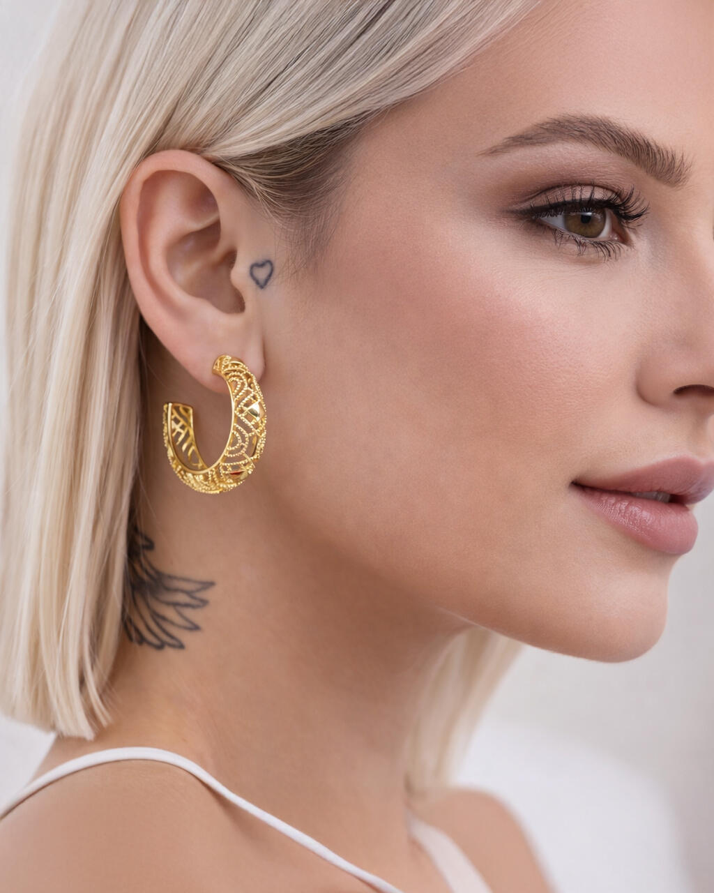Model wearing gold lattice hoop earrings with openwork geometric design and polished gold finis
