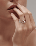 A close-up of a woman's hand wearing a silver open-cuff ring. The minimalist ring features two contrasting polished ends: a s