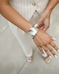 Woman wearing a wide hammered silver cuff bracelet with a reflective textured finish. The elegant open cuff complements her n