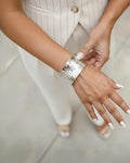 Woman wearing a wide hammered silver cuff bracelet with a reflective textured finish. The elegant open cuff complements her n
