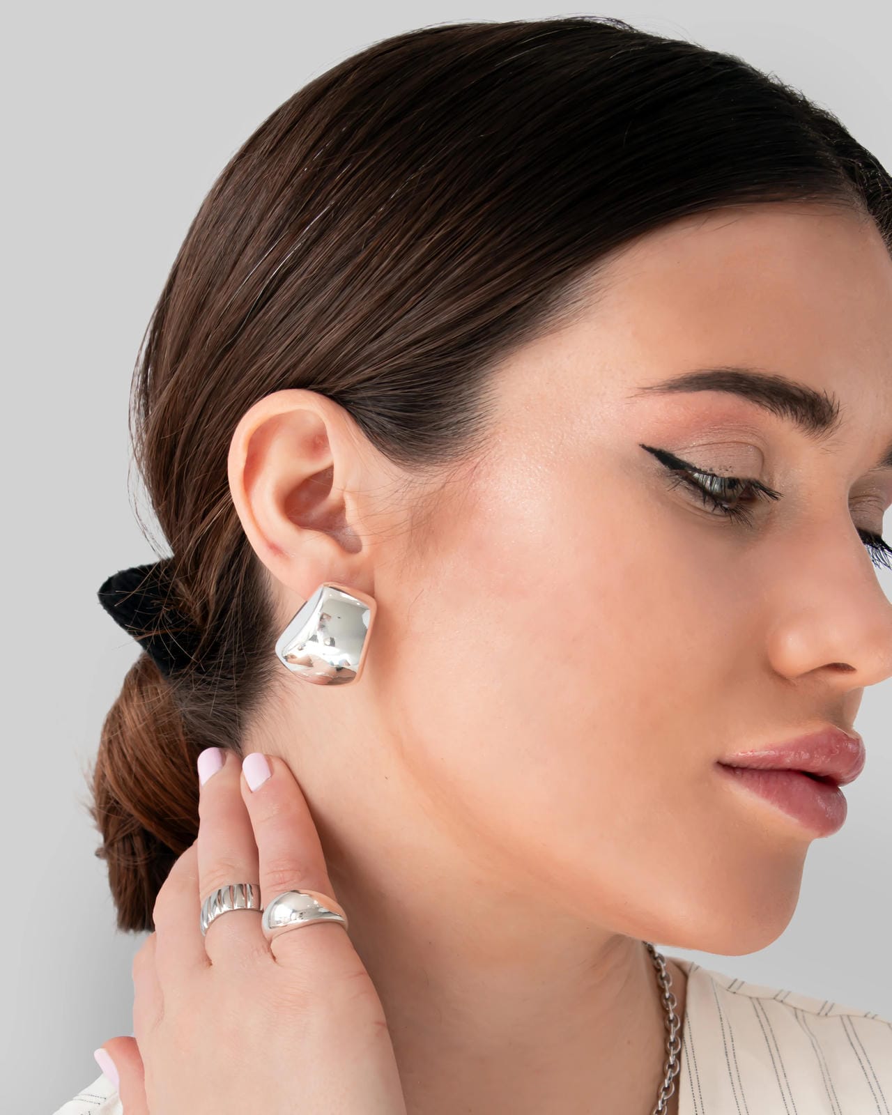 Woman wearing a silver earring with a plain background