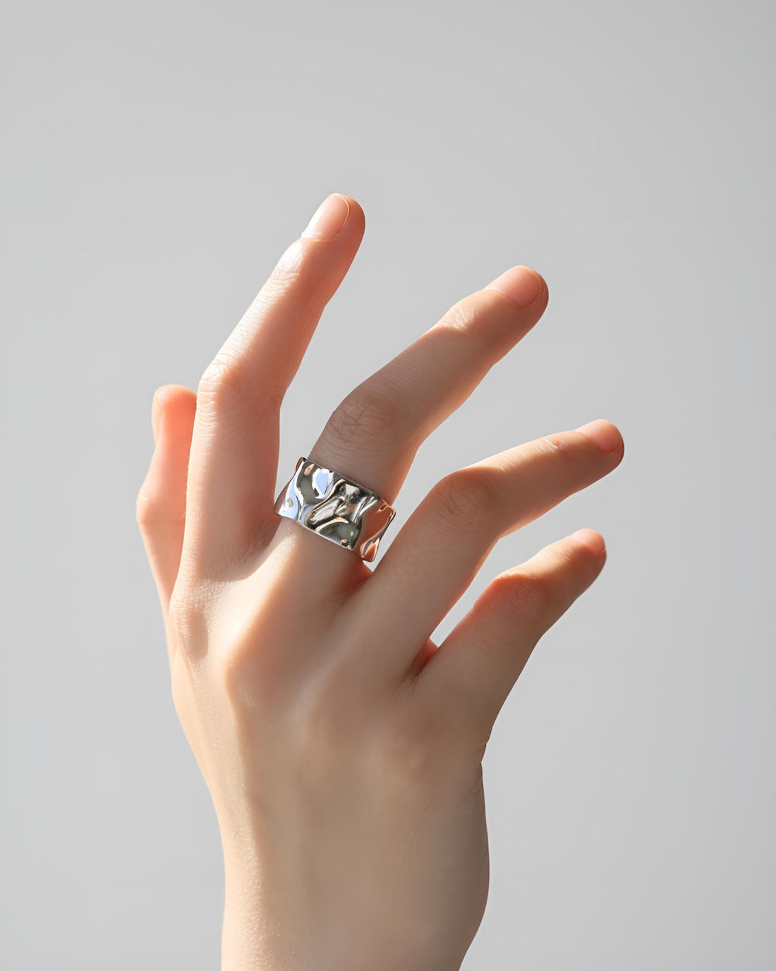 silver-plated ring with molten wave design and open back on white background