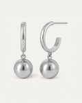 Silver hoop earrings with dangling polished sphere charm in minimalist drop design.
