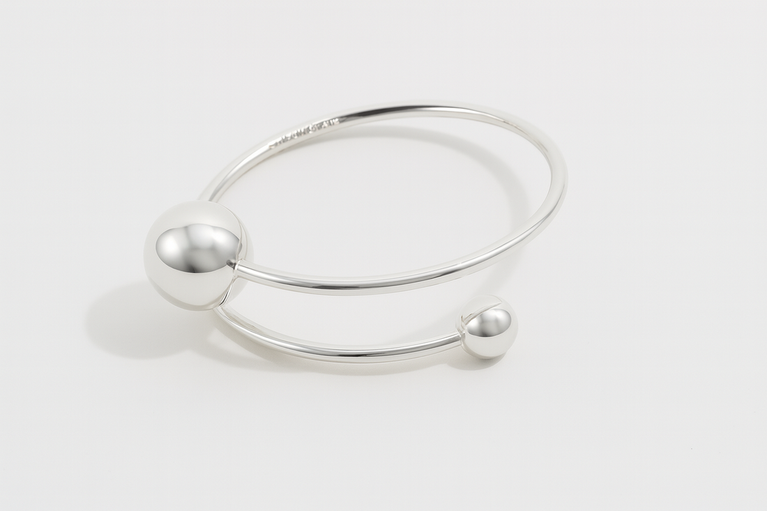 Orbit Dual Sphere Cuff in silver-plated brass featuring two polished spheres in a sleek, sculptural open cuff design.