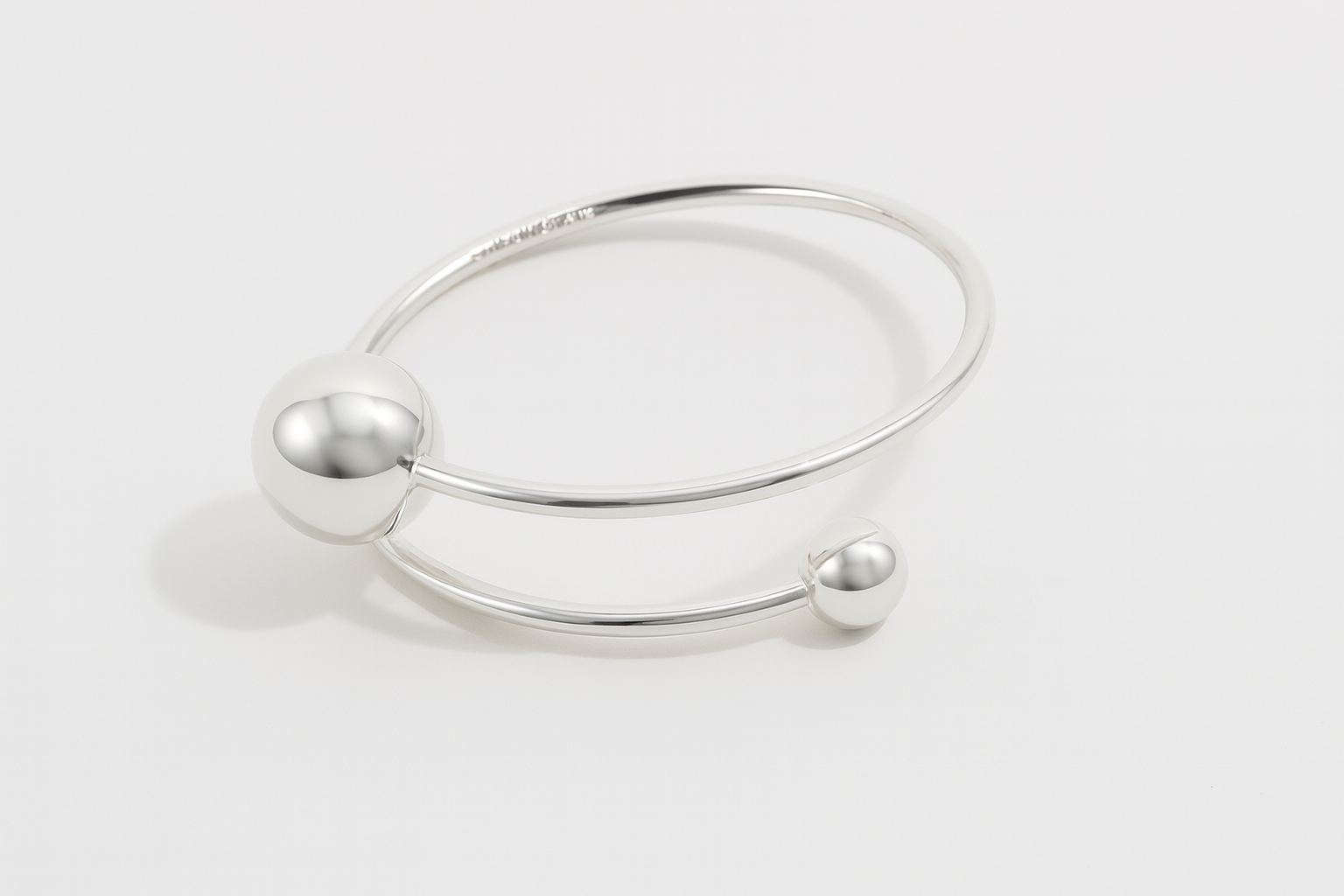 Orbit Dual Sphere Cuff in silver-plated brass featuring two polished spheres in a sleek, sculptural open cuff design.