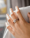 Close-up of a woman's hand resting on a white collar or garment, showcasing a stylish silver-tone Orbit Stack Ring featuring 