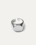 A chunky, adjustable silver signet ring with a minimalist, polished finish. The design features a smooth, oval-shaped top pla