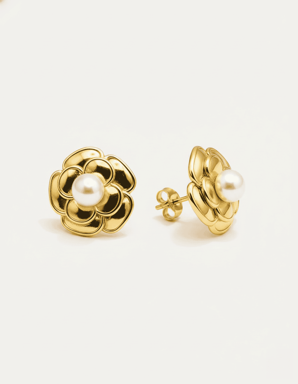 A close-up studio shot of a pair of gold-tone flower stud earrings on a plain white or light beige background. Each earring f