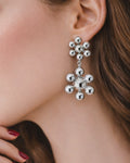 Close-up silver cluster drop earrings with polished bead statement design